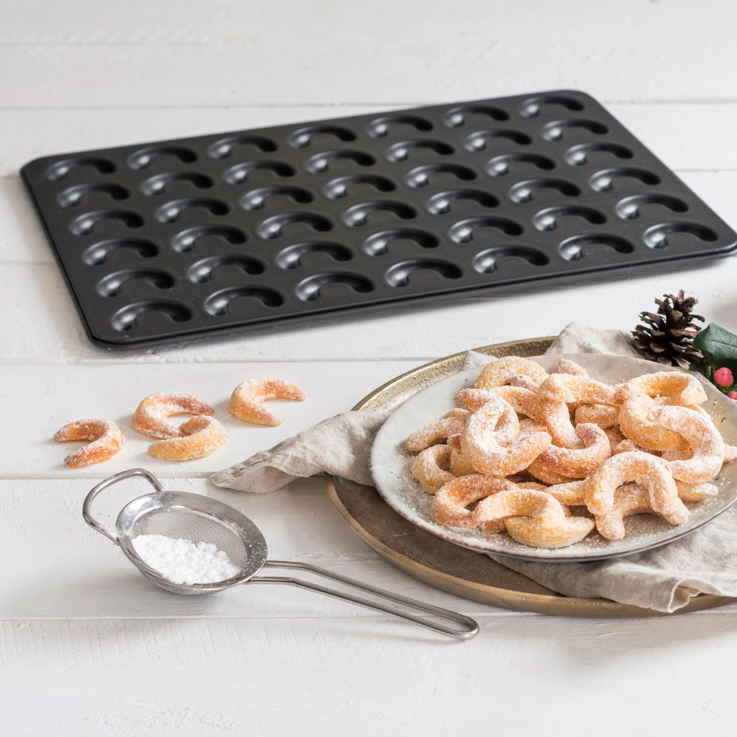 Stimmungsvolles Bild für das Vanillekipferl-Blech mit Vanillekipferln und Puderzucker im Vordergrund