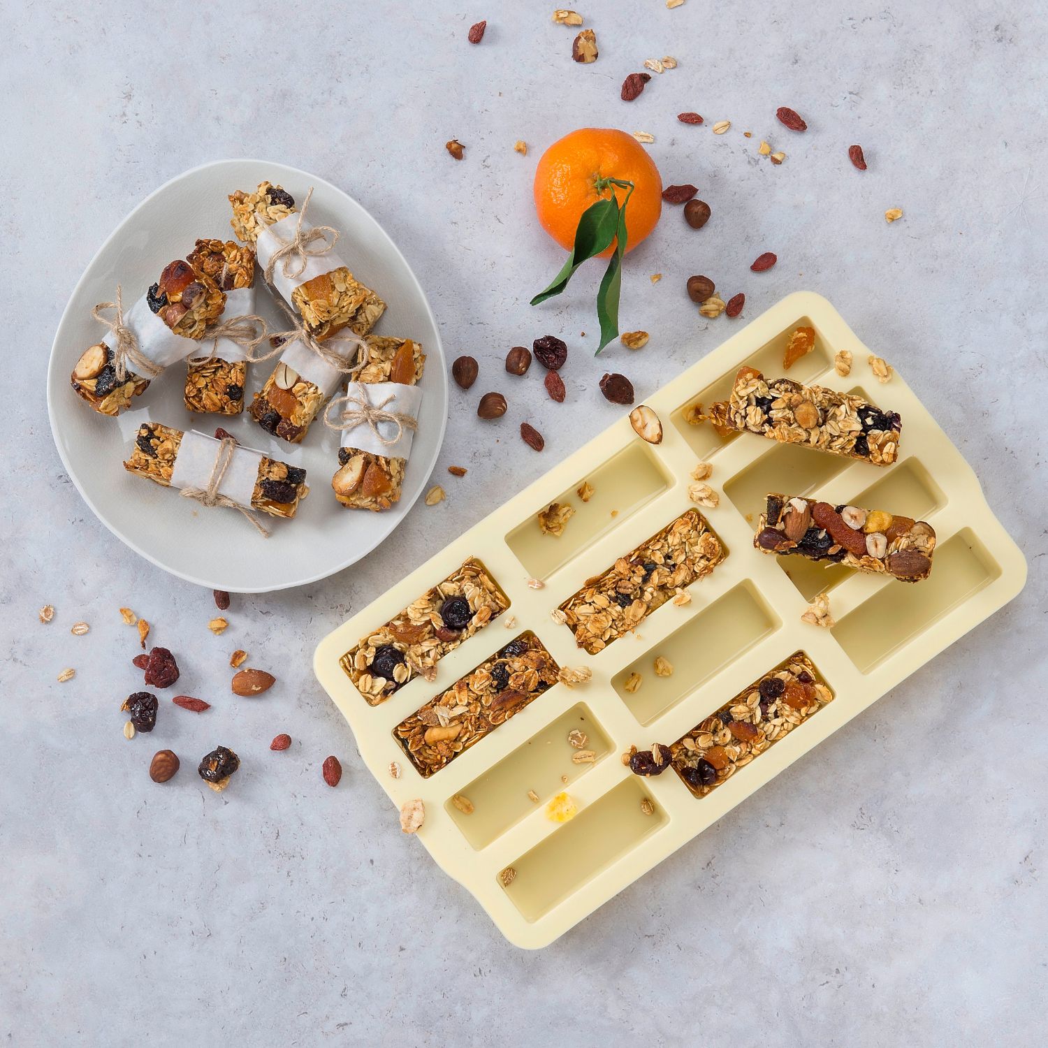 Eine gelbe Silikonform für Minikuchen oder Müsliriegel in Benutzung mit dekorativ gestaltetem Hintergrund  