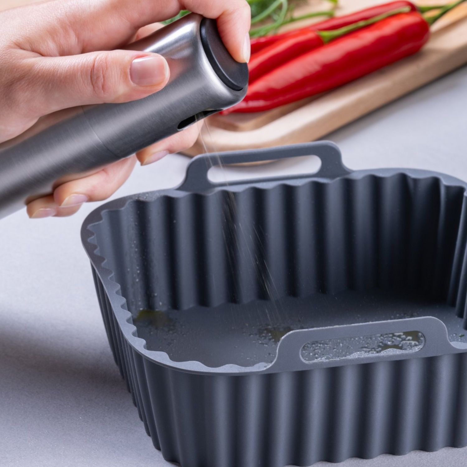 Eine Silikonform für die Heißluftfritteuse, in die Öl gesprüht wird