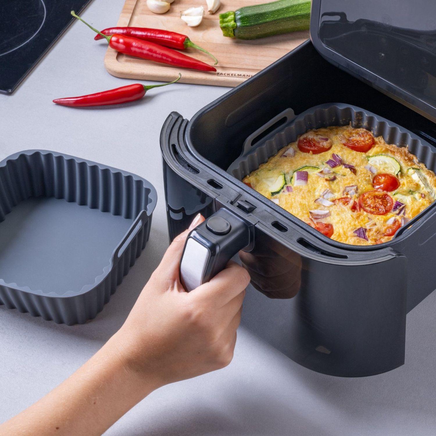 Eckige, graue Silikonform die gerade in die Heißluftfritteuse geschoben wird