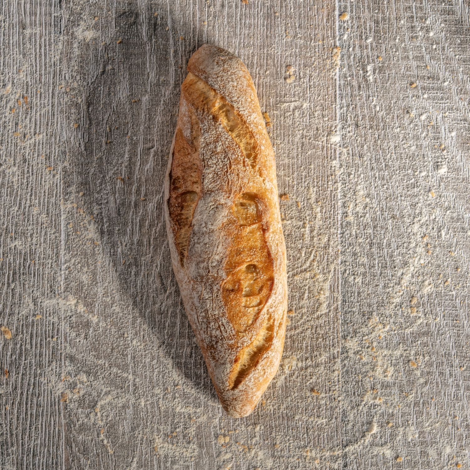 Mini-Baguette auf mehligem Holzhintergrund