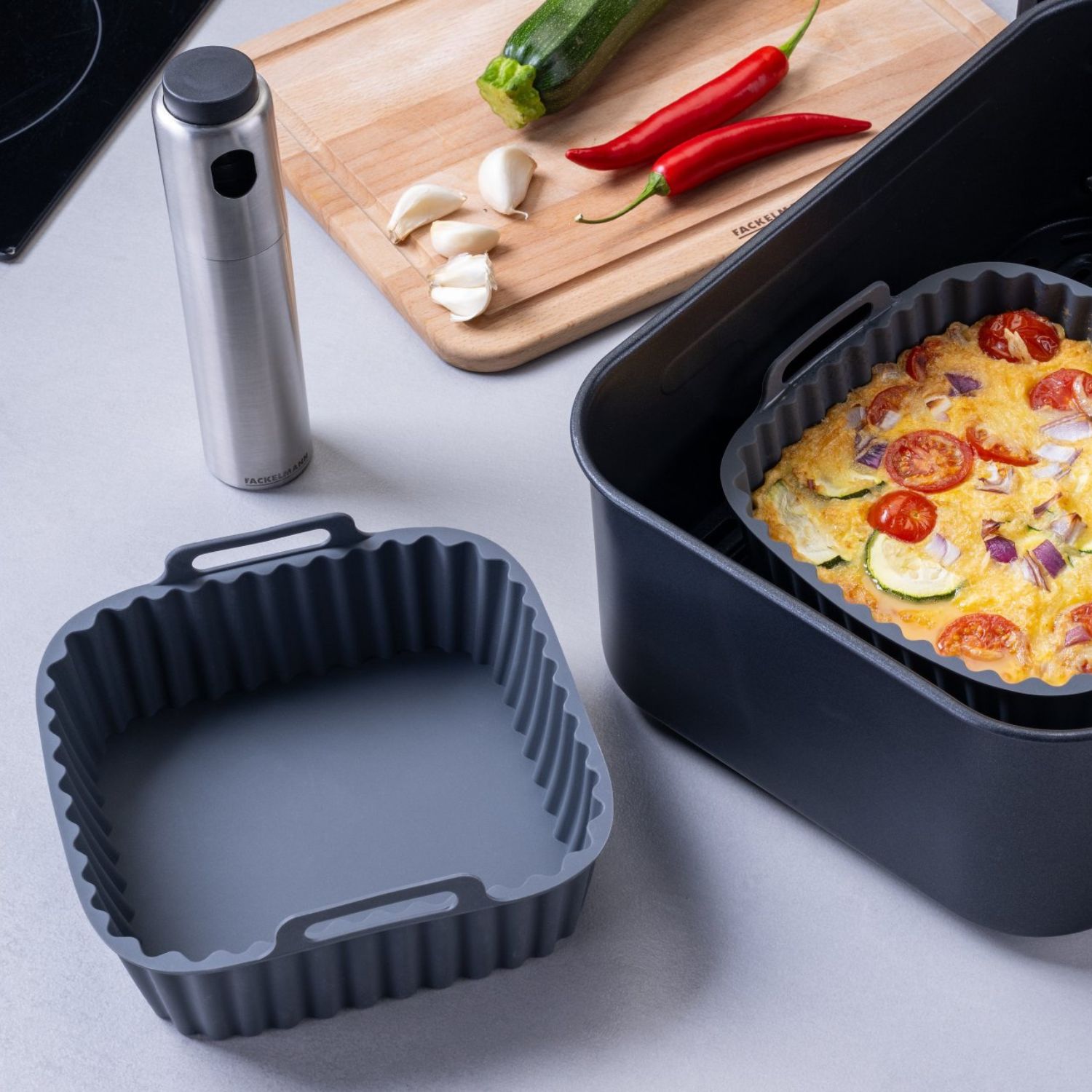 Zwei eckige Silikonformen, eine ist mit Lebensmitteln befüllt und befindet sich in der Heißluftfritteuse