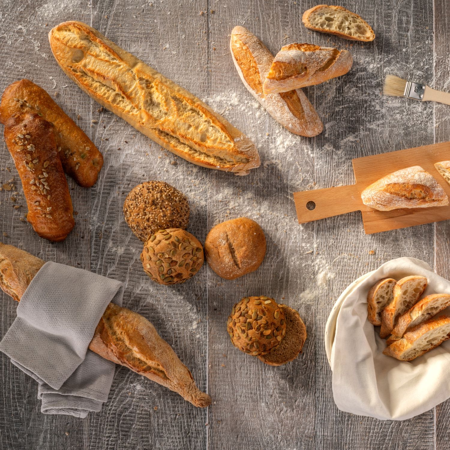 Mini-Baguettes und Brote auf mehliger Holzplatte