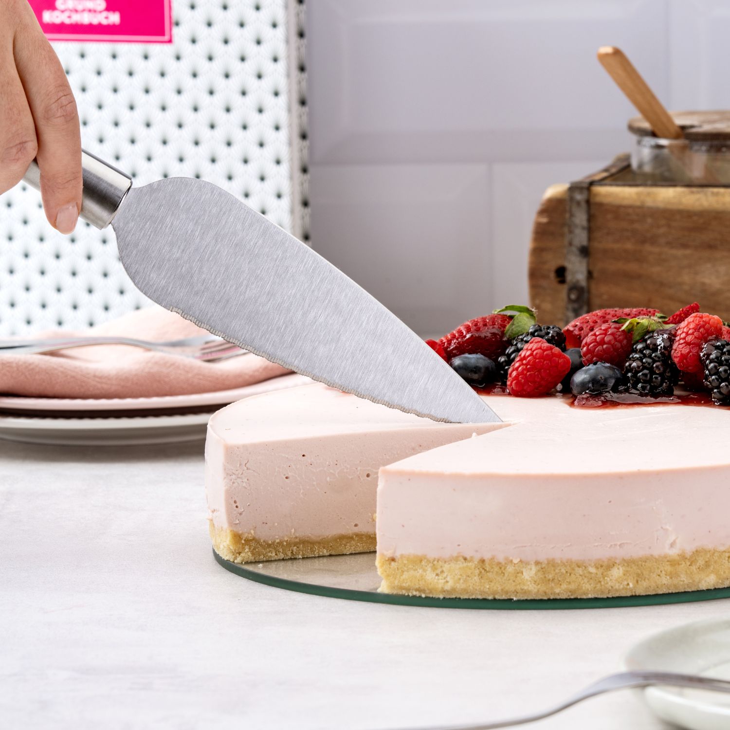 Eine runde Torte mit Früchten, die gerade angeschnitten wird