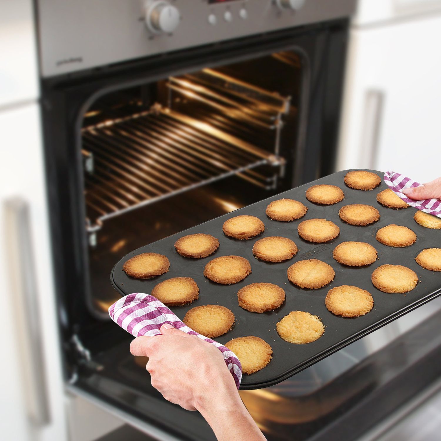 Backblech mit gebackenen Husarenkrapfen wird aus dem Backofen geholt