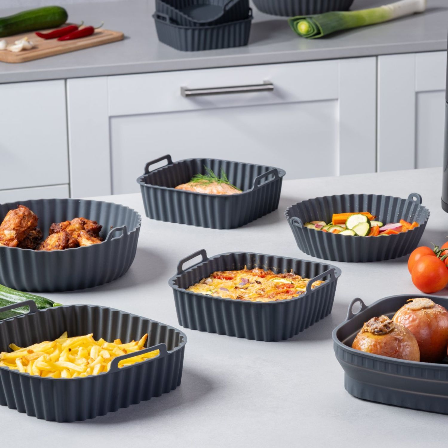 Mehrere Silikonformen für die Heißluftfritteuse in verschiedenen Größen und Formen, befüllt mit unterschiedlichen Gerichten
