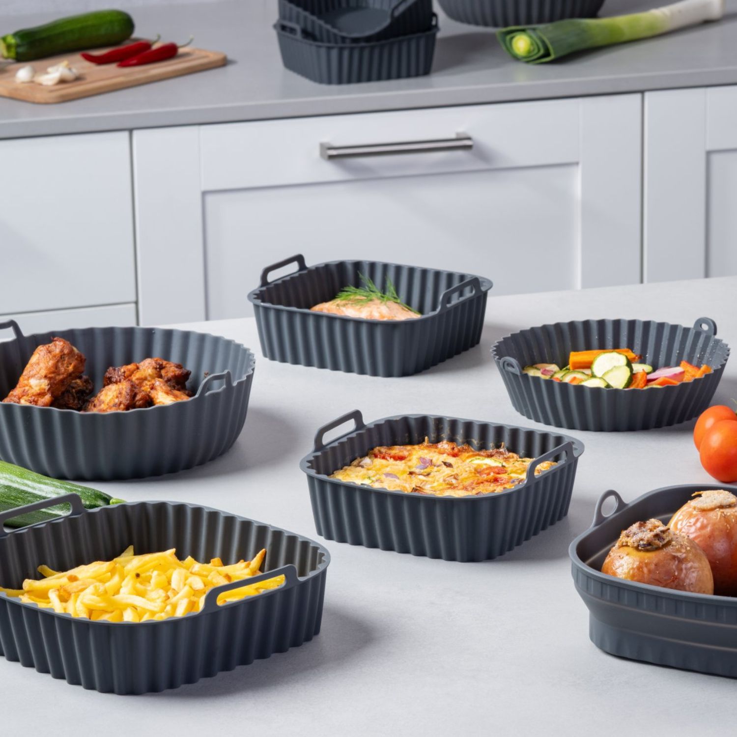 Mehrere Silikonformen für die Heißluftfritteuse in verschiedenen Größen und Formen, befüllt mit unterschiedlichen Gerichten