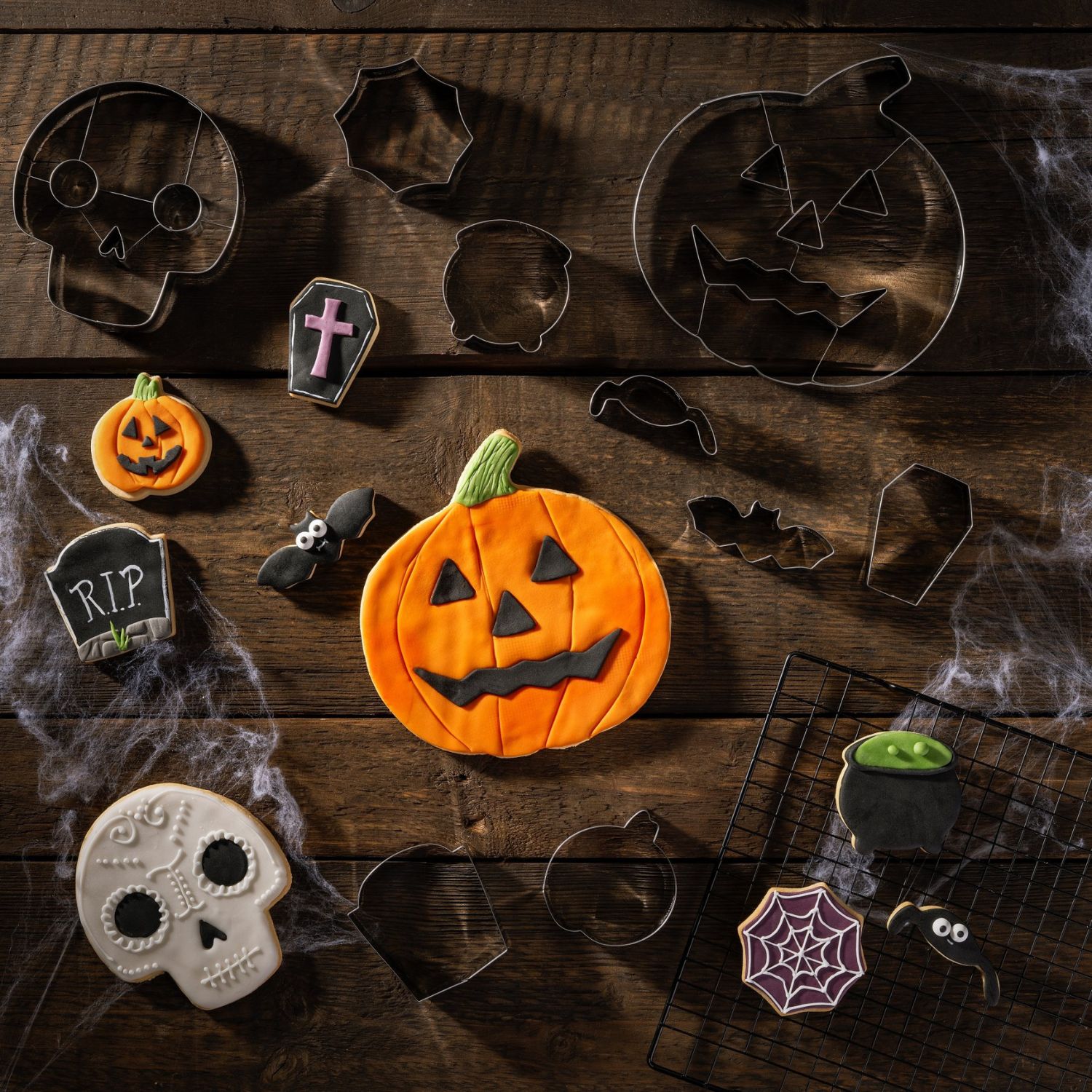Kekse und Ausstecher in Halloween-Motiven auf Holzhintergrund