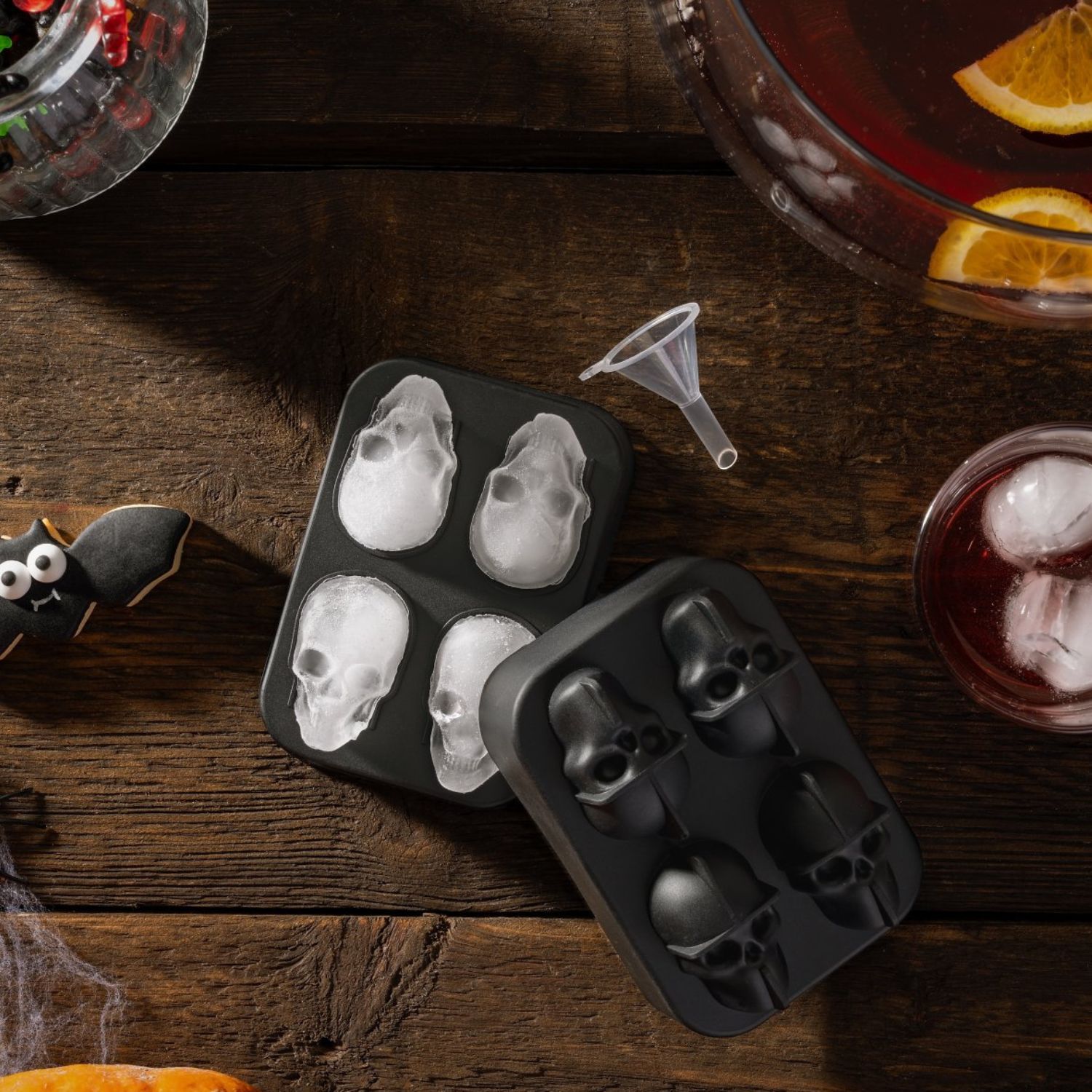 Moodbild für einen Eiswürfelformer für Totenkopf-Motive neben Bowle und auf Holzhintergrund