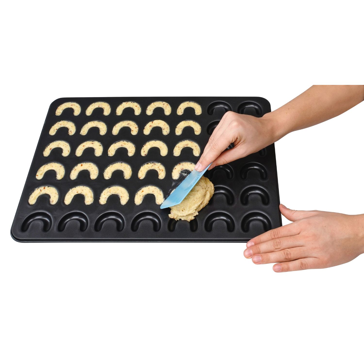 Teig wird mit einem Teigschaber auf dem Vanillekipferl-Backblech verstrichen