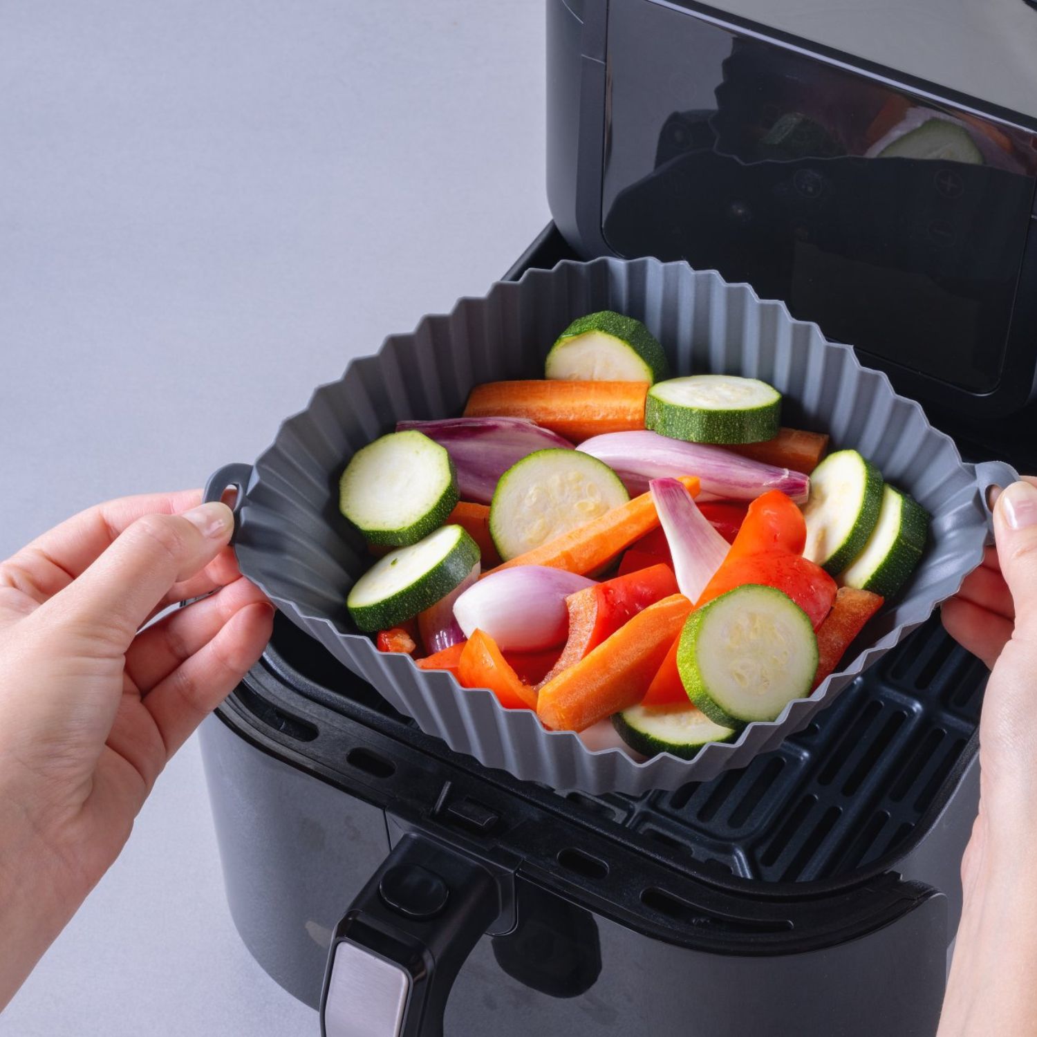 Eine runde Silikonform mit Gemüse, die in die Heißluftfritteuse gelegt wird