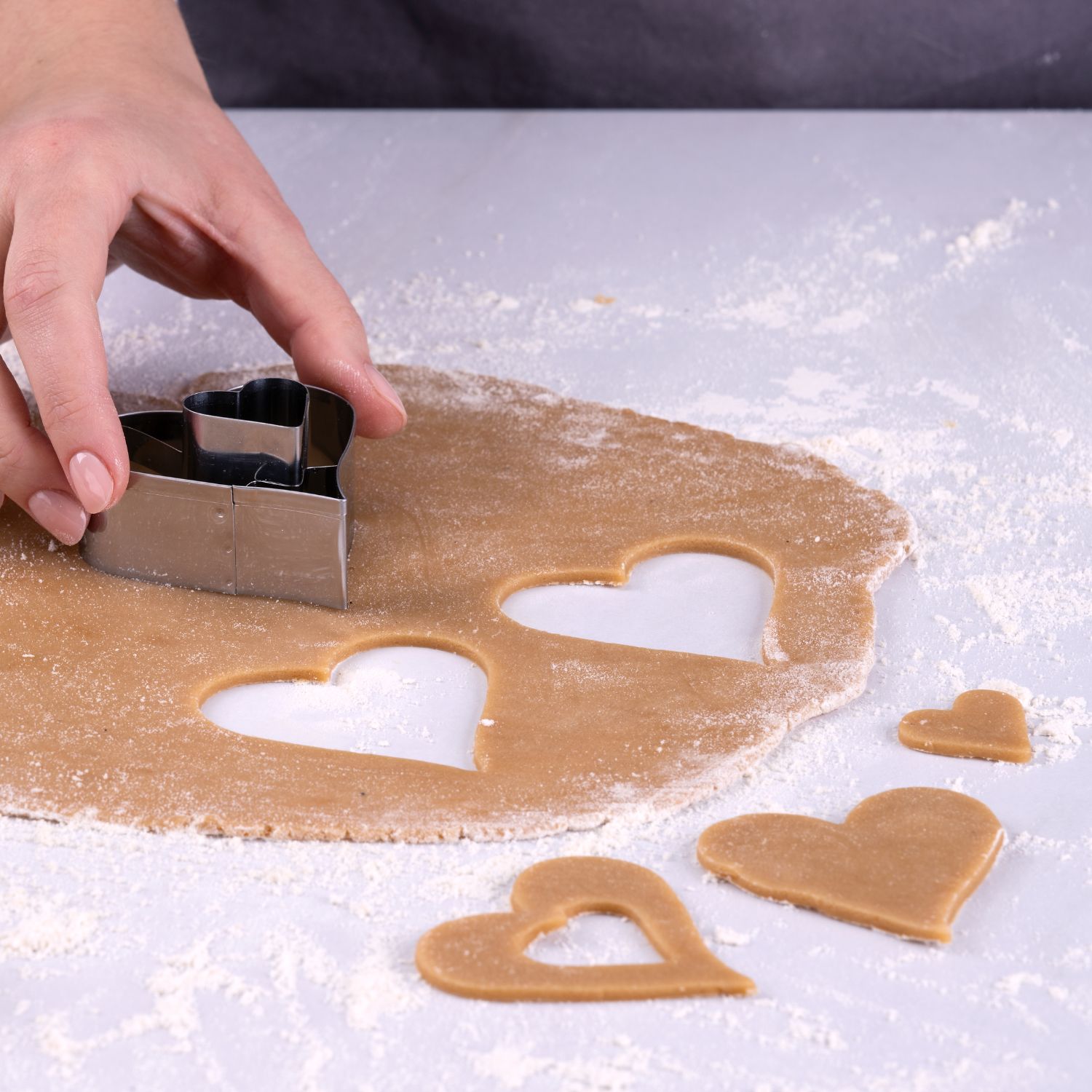 Hand die Linzer Herz-Plätzchen aus ausgerolltem Teig aussticht