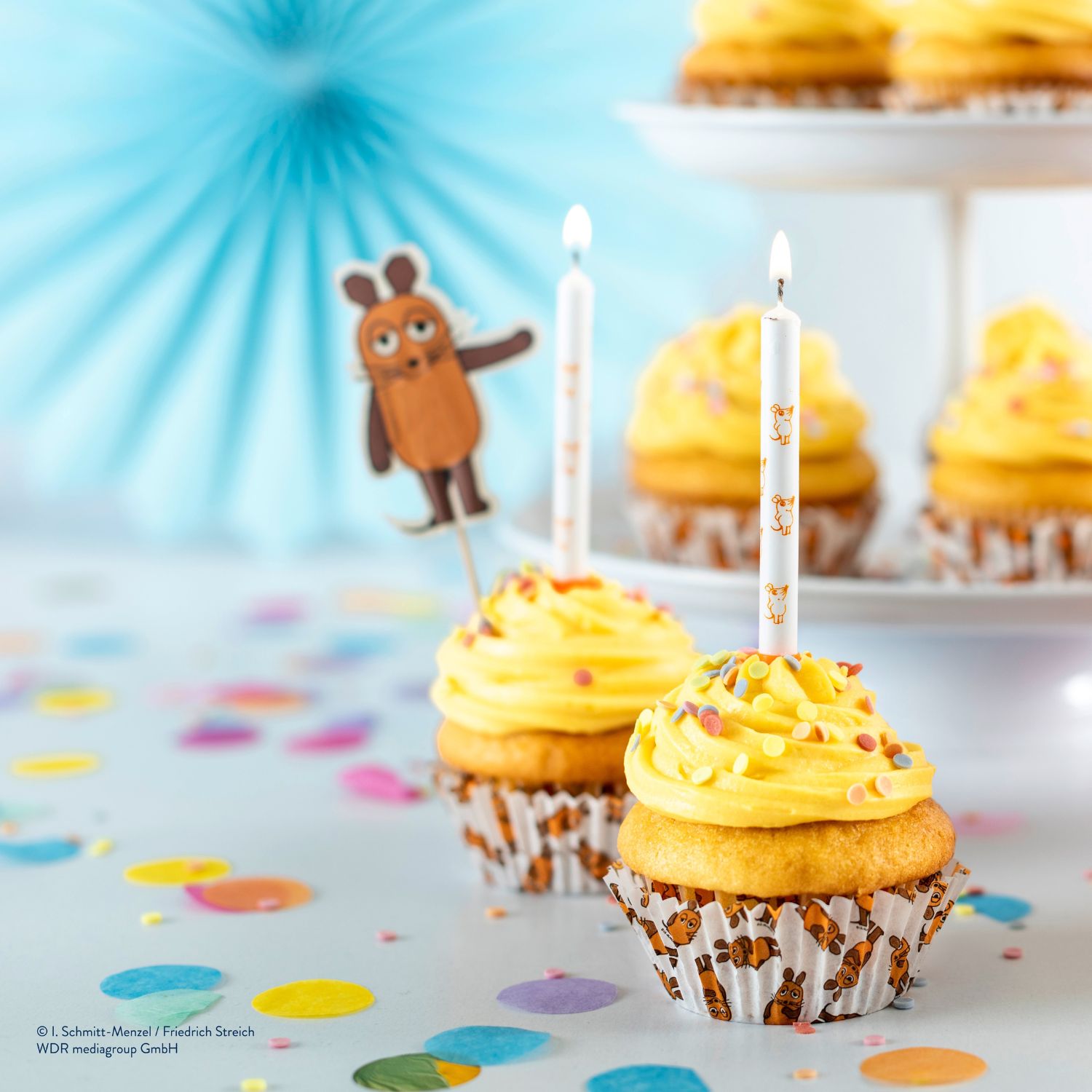 Papierbackförmchen Maus mit Cupcakes vor Etagere und Party-Hintergrund
