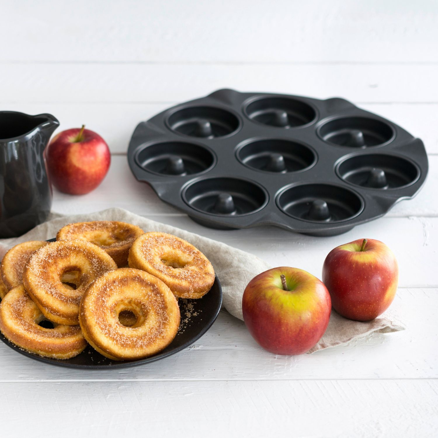 Stimmungsvolles Bild mit Backblech für Apfelkuechli auf Hlzuntergrund und mit Äpfeln und fertigen Apfelkuechli