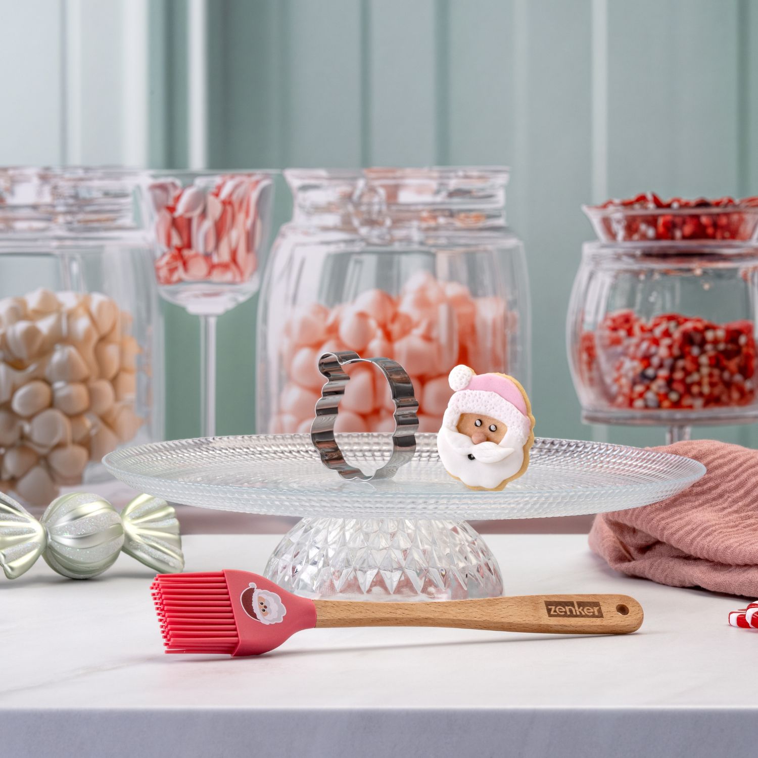 weihnachtlicher Backhelfer mit Motiv eines Weihnachtsmannes und passendem Ausstecher vor dekorativem Hintergrund aus Süßigkeiten