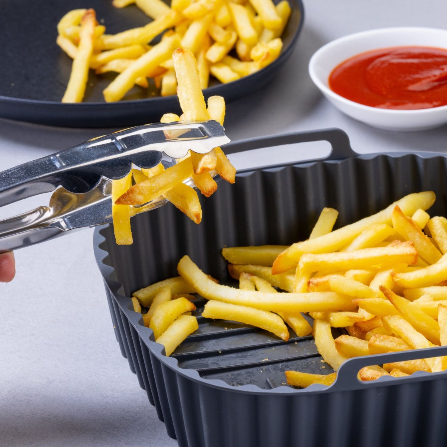 Silikonform gefüllt mit Pommes, im Hintergrund steht ein Teller und Ketchup