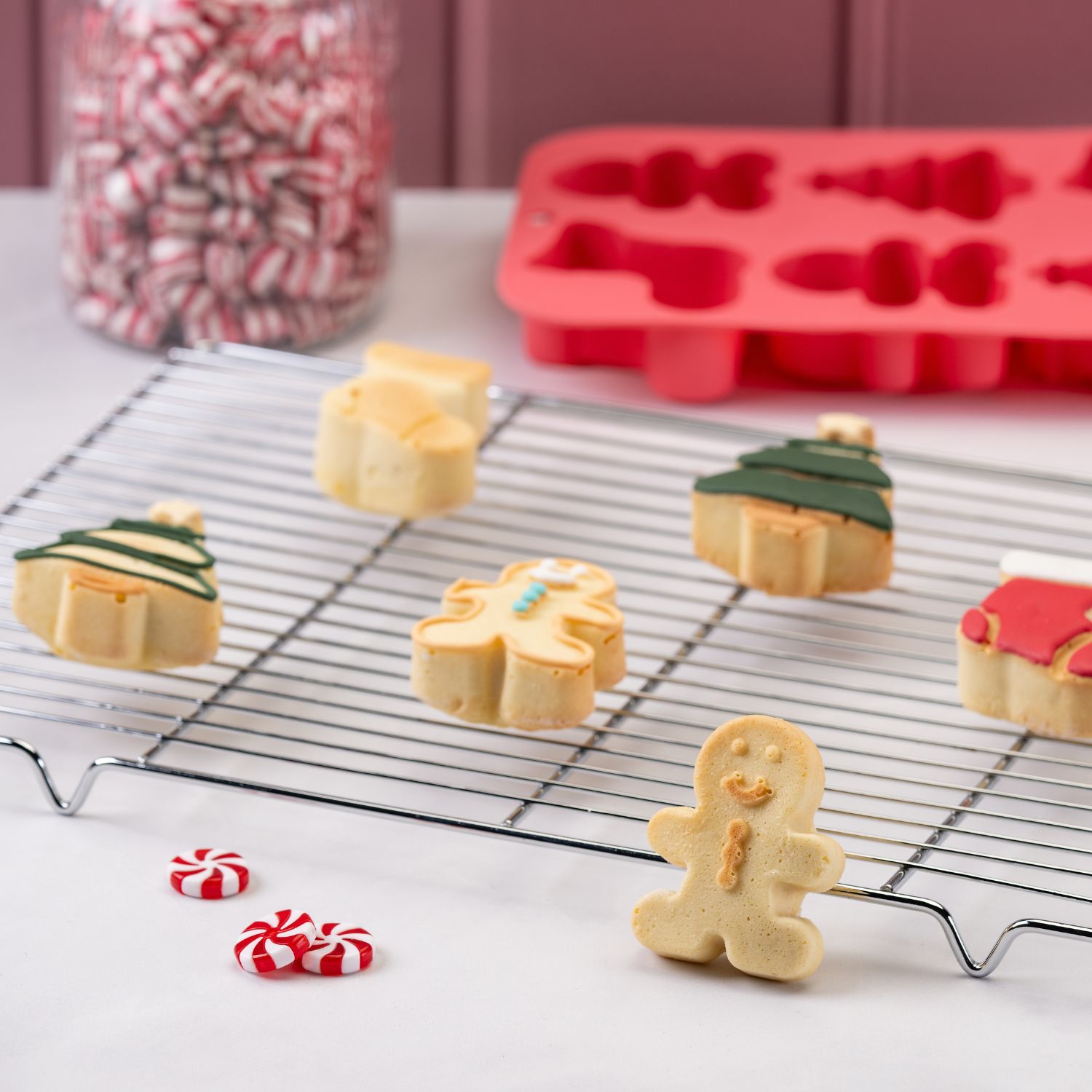 fertige Gebäcke auf einem Kuchenrost und vor einer roten Silikonbackform mit weihnachtlichen Motiven
