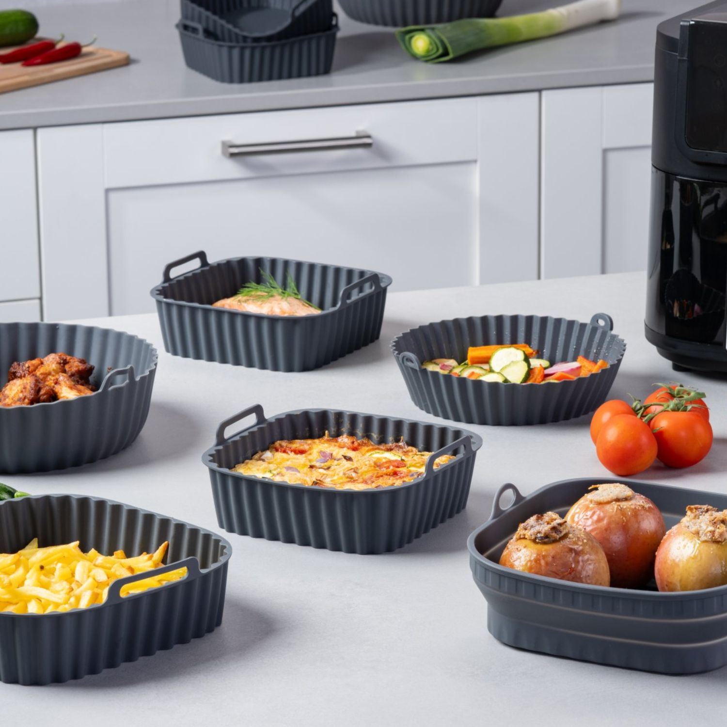Mehrere Silikonformen für die Heißluftfritteuse in verschiedenen Größen und Formen, befüllt mit unterschiedlichen Gerichten