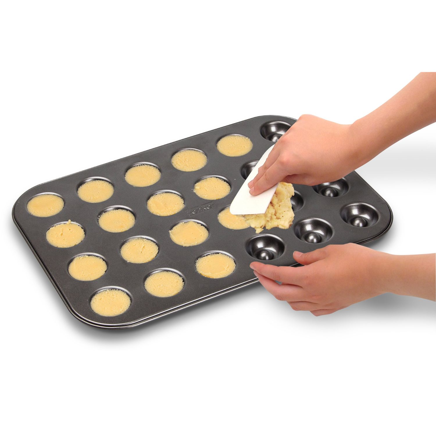 Teig wird mit einem Teigschaber in ein Backblech fuer Husarenkrapfen gestrichen